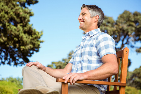 Casual man relaxing on park bench on a sunny dayの写真素材