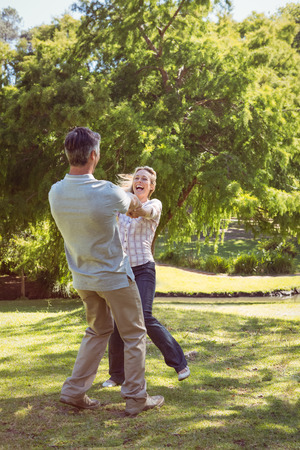 Happy couple dancing in the park on a sunny dayの写真素材