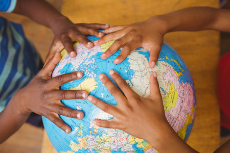Close up of hands on globe in classroom