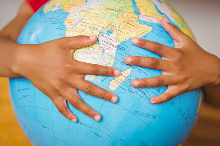 Close up of hands on globe in classroomの写真素材