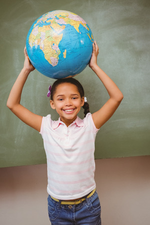 Portrait of cute little girl holding globe over headの写真素材
