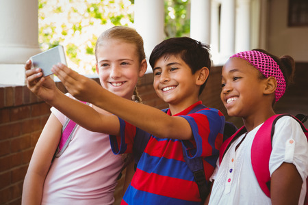 Portrait of happy little school kids taking selfie in school corridorの写真素材