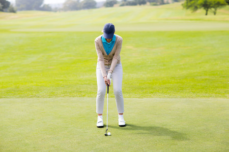 Female golfer putting her ball on a sunny day at the golf courseの写真素材