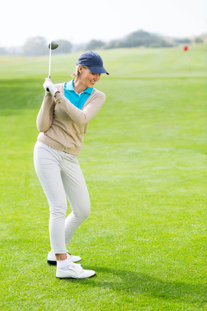 Female golfer taking a shot on a sunny day at the golf coursの写真素材