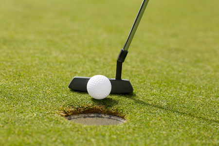 Golf club putting ball at the hole on a sunny day at the golf course