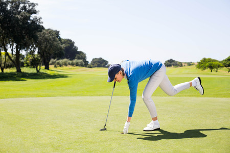 Female golfer picking up golf ball on a sunny day at the golf courseの写真素材