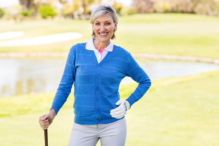 Female golfer smiling at camera on a sunny day at the golf courseの写真素材