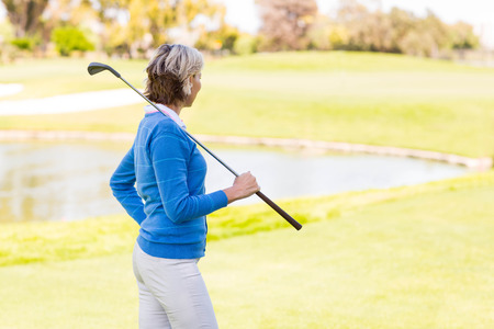 Female golfer standing holding her club on a sunny day at the golf courseの写真素材