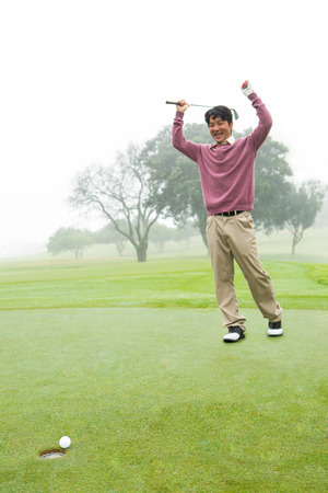 Excited golfer cheering on putting green at the golf courseの写真素材