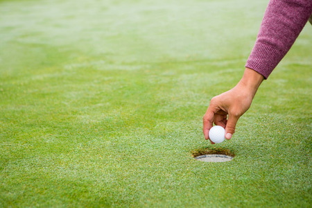 Golfer trying to flick ball into hole at the golf courseの写真素材