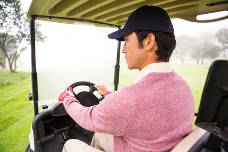Golfer driving his golf buggy at the golf courseの写真素材