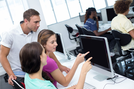 Computer teacher helping pretty female students in his class