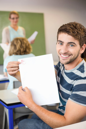 Portrait of happy male student holding paper in the classの写真素材