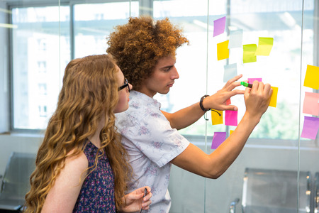 Creative business team looking at adhesive notes in office
