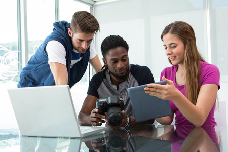 Creative young business team looking at digital tablet at office desk