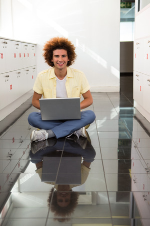 Portrait of smiling young man using laptop on floorの写真素材