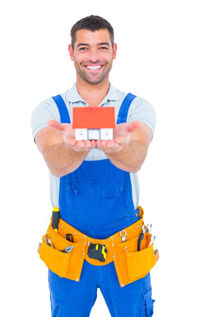 Portrait of happy construction worker holding house model on white backgroundの写真素材