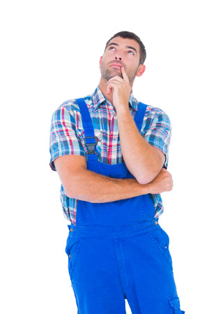 Thoughtful handyman in coveralls looking up on white backgroundの写真素材