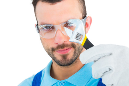 Repairman looking through adjustable wrench on white background