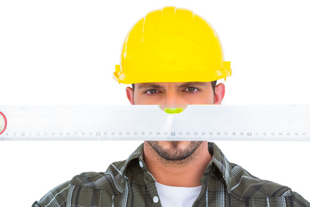 Handyman looking at spirit level over white background