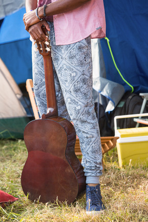 Hipster holding guitar at campsite on a sunny dayの写真素材