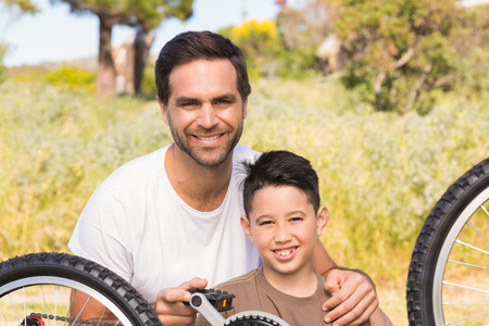 Father and son repairing bike together on a sunny dayの写真素材