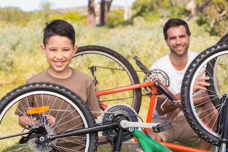 Father and son repairing bike together on a sunny dayの写真素材