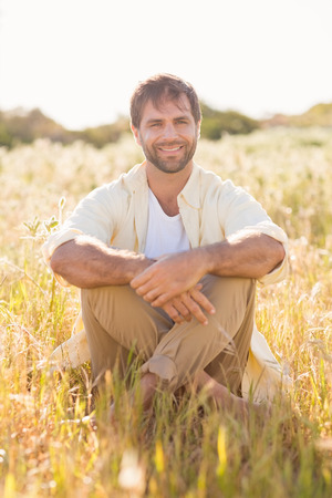 Happy man smiling at camera on a sunny dayの写真素材