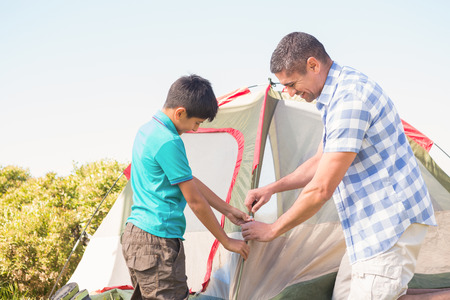 Father and son pitching their tent on a sunny dayの写真素材