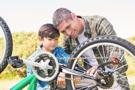 Father and son repairing bike on a sunny dayの写真素材