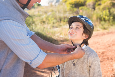 Father clipping on sons helmet on a sunny dayの写真素材