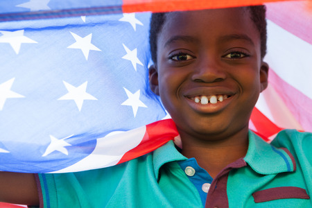 Happy boy in the park with american flag on a sunny dayの写真素材