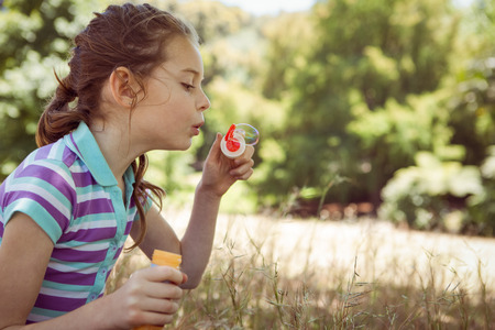 Cute little girl blowing bubbles on a sunny dayの写真素材