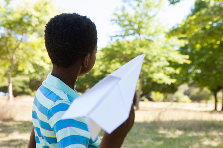 Cute little boy with paper airplane on a sunny dayの写真素材