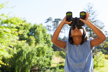 Cute little girl looking through binoculars on a sunny dayの写真素材