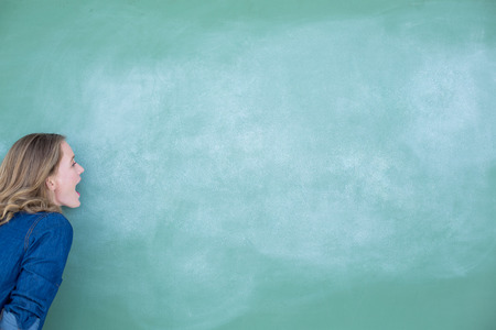 Smiling teacher standing in front of blackboard in classroomの写真素材
