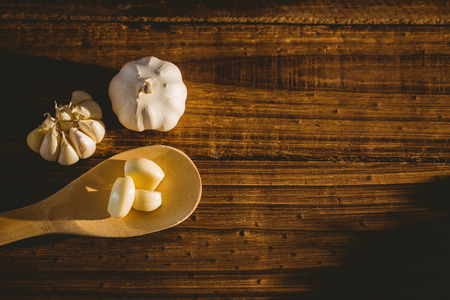 Garlic cloves and bulb on chopping board with copy spaceの写真素材