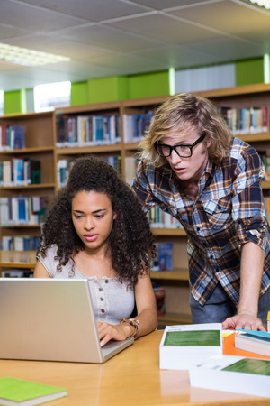 Student getting help from classmate in library at the universityの写真素材