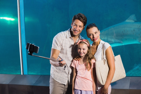 Happy family using selfie stick at the aquariumの写真素材
