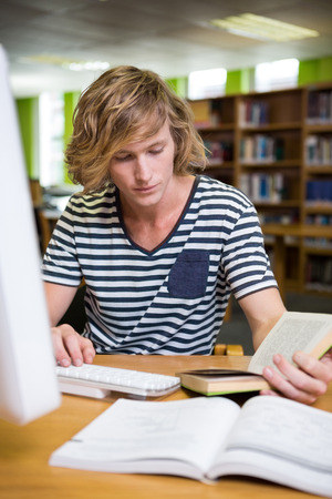 Student studying in the library with computer at the universityの写真素材