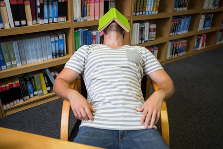 Student asleep in the library with book on his face at the universityの写真素材