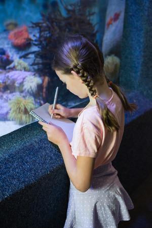 Cute girl looking at fish tank at the aquariumの写真素材