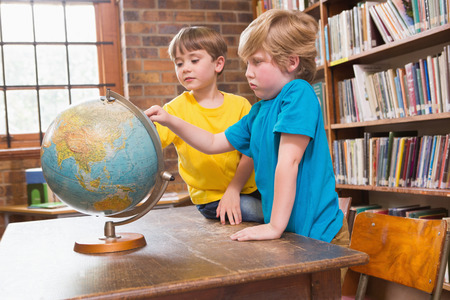 Cute pupils looking at globe at elementary schoolの写真素材