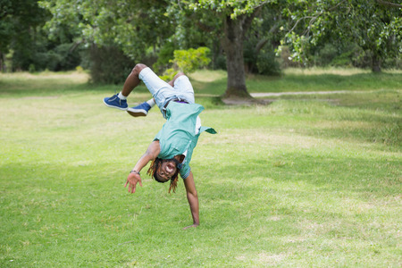 Hipster doing back flip in the park on a sunny dayの写真素材