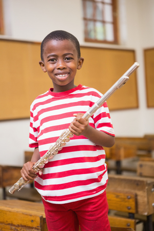 Happy pupil holding flute at elementary schoolの写真素材