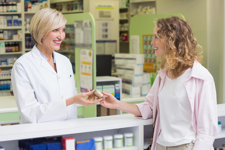 Pharmacist and costumer holding medicine jar at pharmacyの写真素材