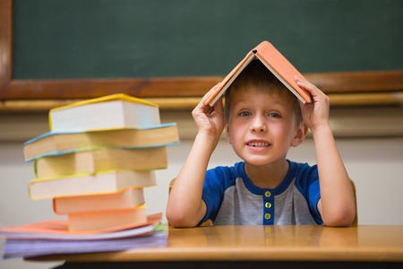 Cute boy with book on head at the elementary schoolの写真素材