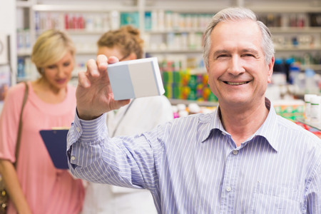 Costumer holding up medicine box at pharmacyの写真素材