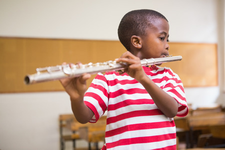 Cute pupil playing flute in classroom at the elementary schoolの写真素材