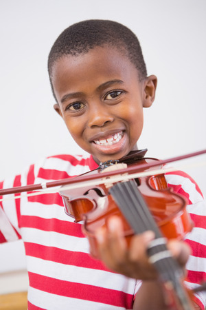 Happy pupil playing violin in classroom at the elementary schoolの写真素材